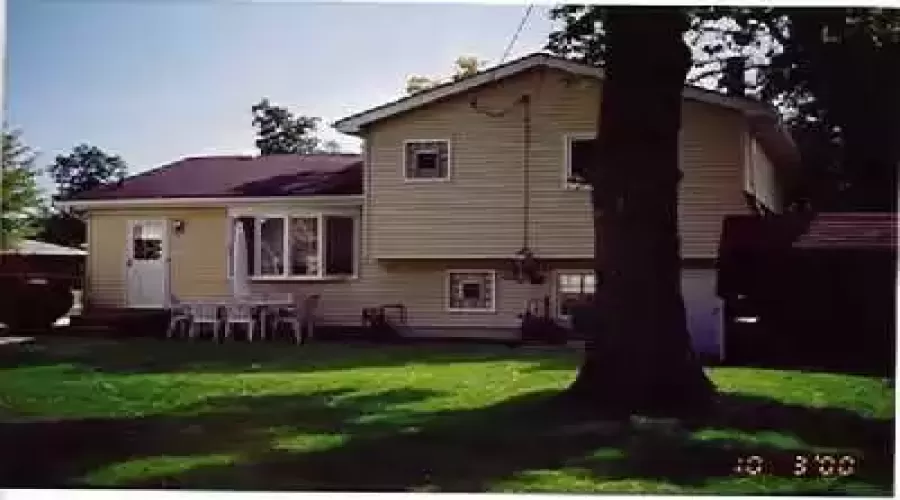 Here's a great view of the rear of the home - note the shed on the right - a beautiful mature shade tree - patio - bow window in kitchen and block windows in upper and lower baths!