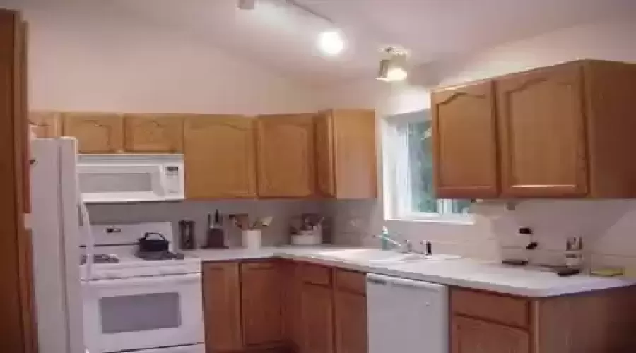 Oak kitchen with vaulted ceiling,skylight and view of woods out back. Neutral decor.